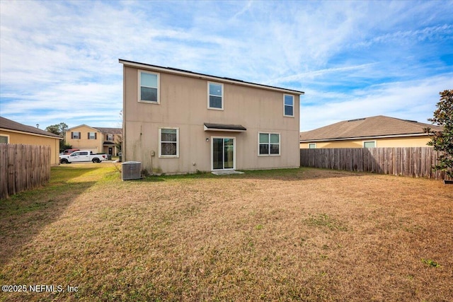 rear view of house with cooling unit and a lawn