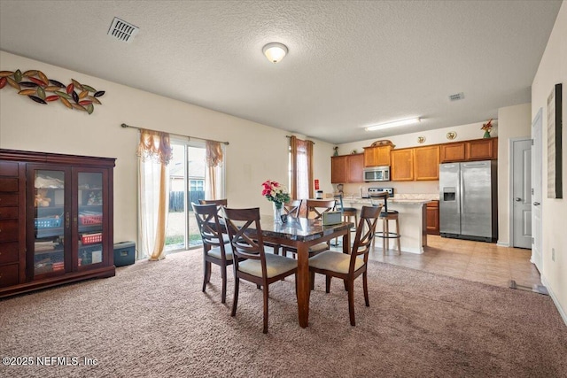 carpeted dining area with a textured ceiling