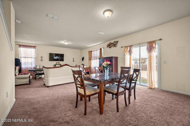 carpeted dining room featuring a textured ceiling