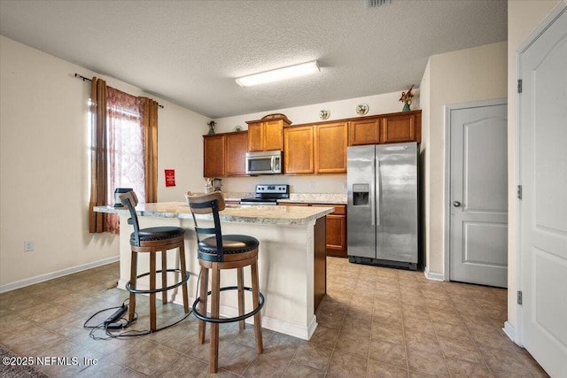 kitchen with a kitchen breakfast bar, a center island, a textured ceiling, and stainless steel appliances