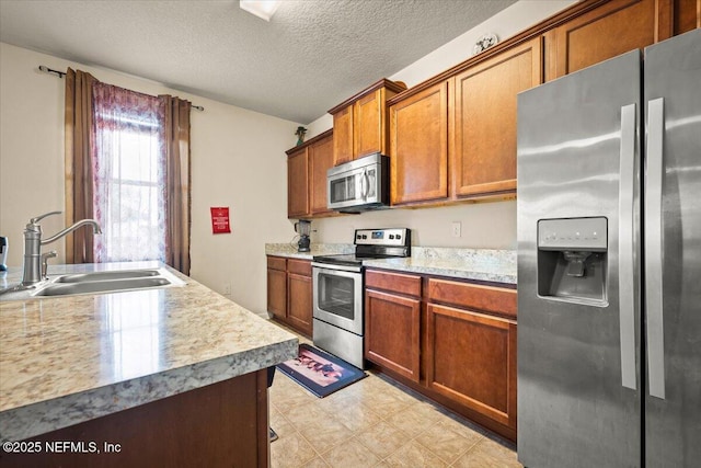 kitchen with sink, a textured ceiling, and appliances with stainless steel finishes