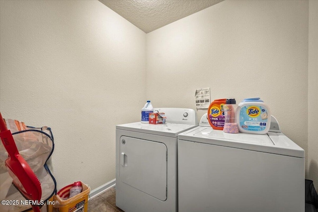 laundry room with dark tile patterned flooring, a textured ceiling, and washer and clothes dryer