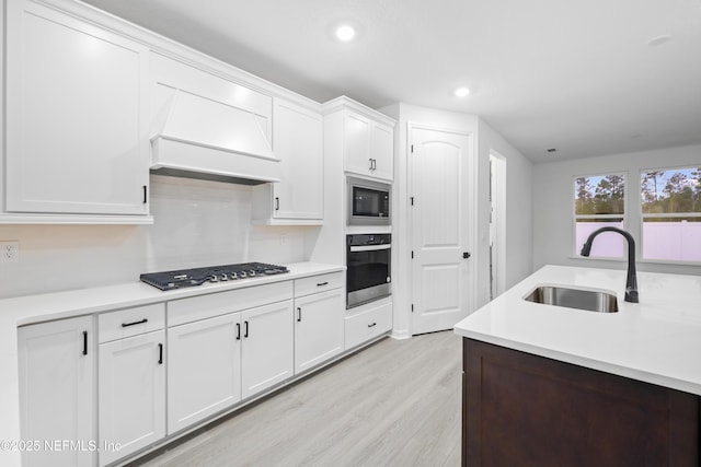 kitchen featuring premium range hood, built in microwave, stainless steel gas cooktop, white cabinetry, and oven