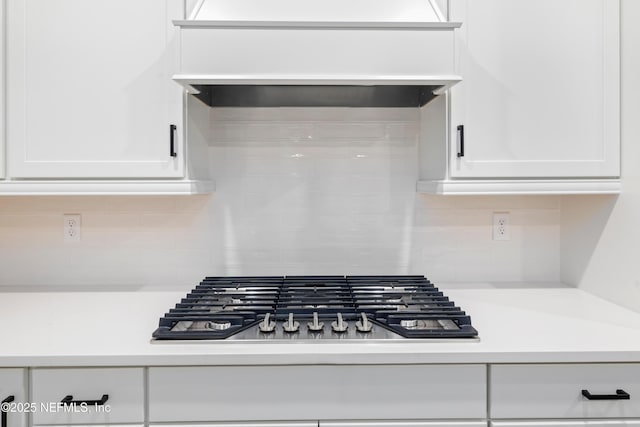 room details featuring white cabinetry, decorative backsplash, and stainless steel gas cooktop