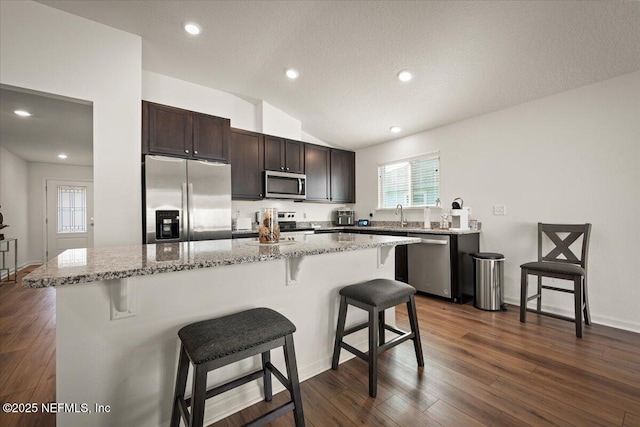 kitchen featuring a kitchen breakfast bar, stainless steel appliances, lofted ceiling, and a kitchen island