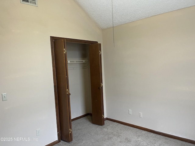 unfurnished bedroom with baseboards, visible vents, carpet floors, lofted ceiling, and a textured ceiling