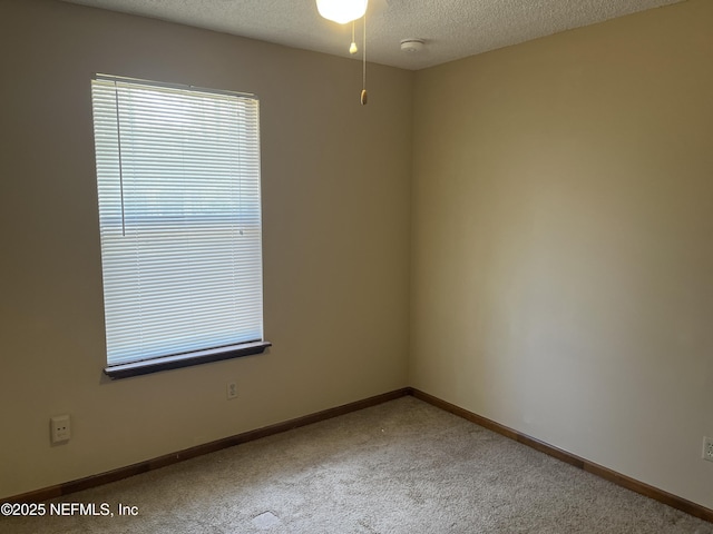 carpeted empty room with baseboards and a textured ceiling