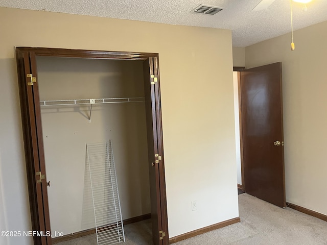 unfurnished bedroom featuring baseboards, visible vents, a closet, a textured ceiling, and light colored carpet