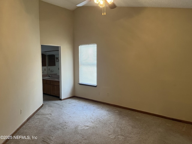 unfurnished bedroom with ensuite bath, high vaulted ceiling, baseboards, and light carpet