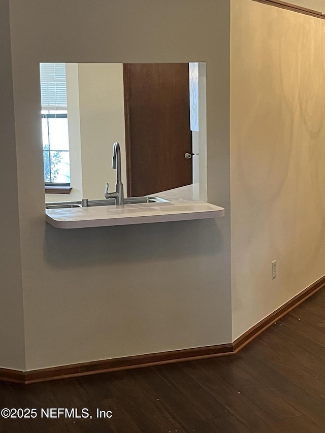 kitchen featuring a sink, dark wood finished floors, a peninsula, light countertops, and baseboards