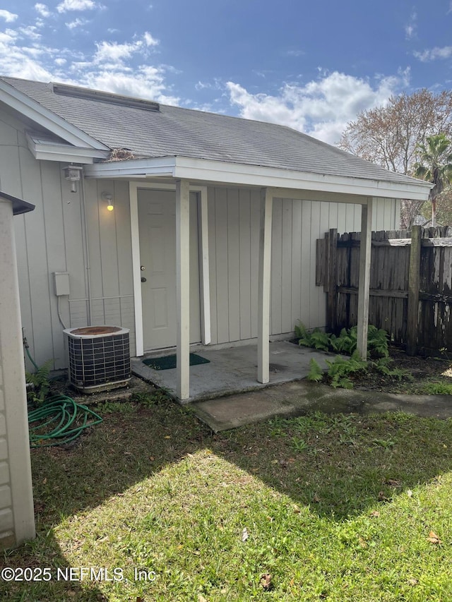 view of outdoor structure with central AC unit and fence