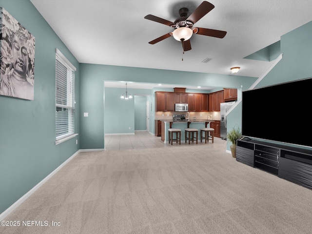 carpeted living room featuring ceiling fan with notable chandelier