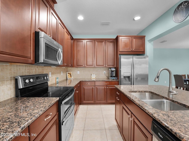 kitchen with light tile patterned flooring, appliances with stainless steel finishes, sink, and dark stone countertops