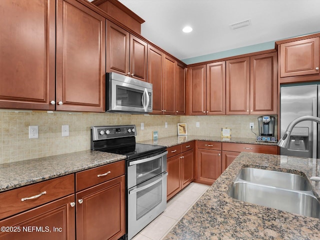 kitchen with light stone counters, appliances with stainless steel finishes, sink, and light tile patterned floors