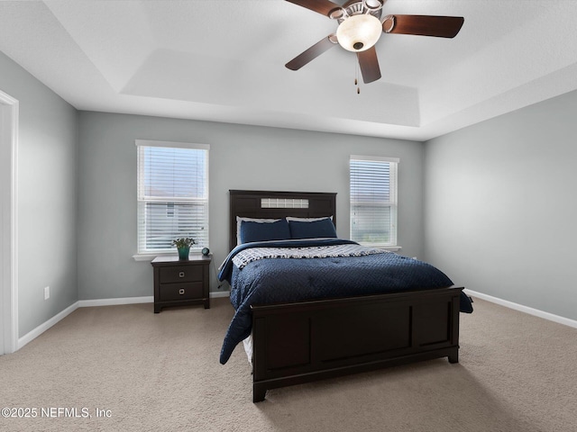 bedroom with a tray ceiling, light colored carpet, and ceiling fan