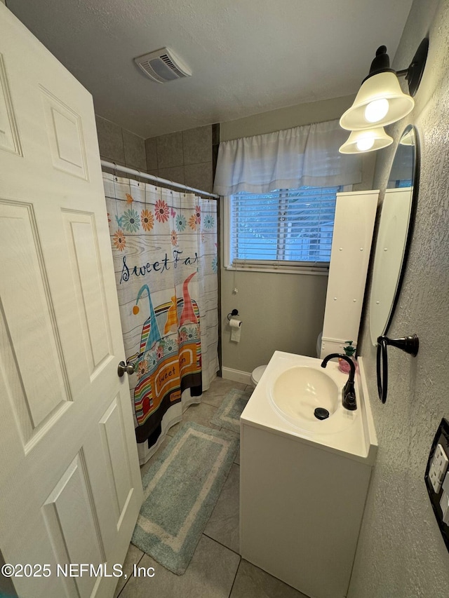 bathroom with a textured ceiling, tile patterned flooring, vanity, and curtained shower