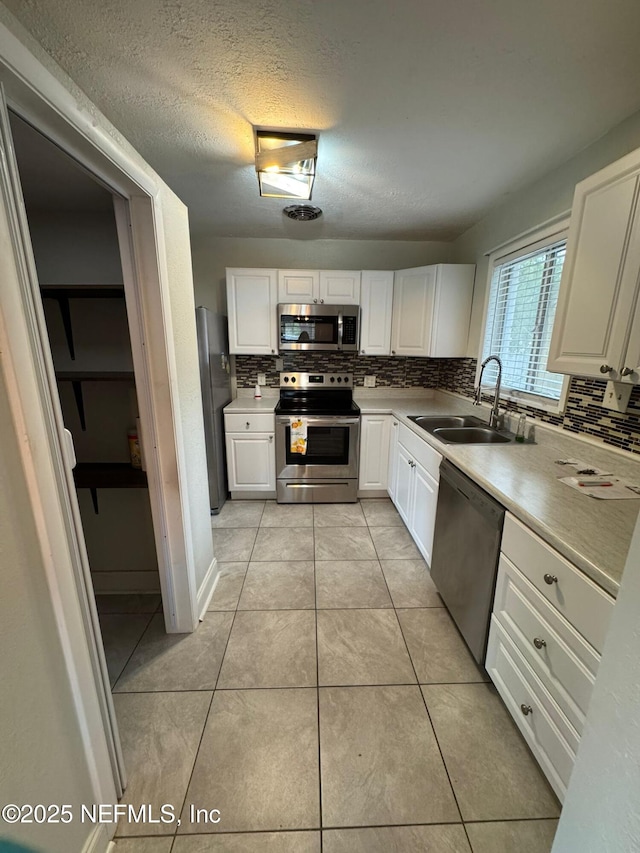 kitchen featuring light tile patterned flooring, stainless steel appliances, white cabinets, and sink