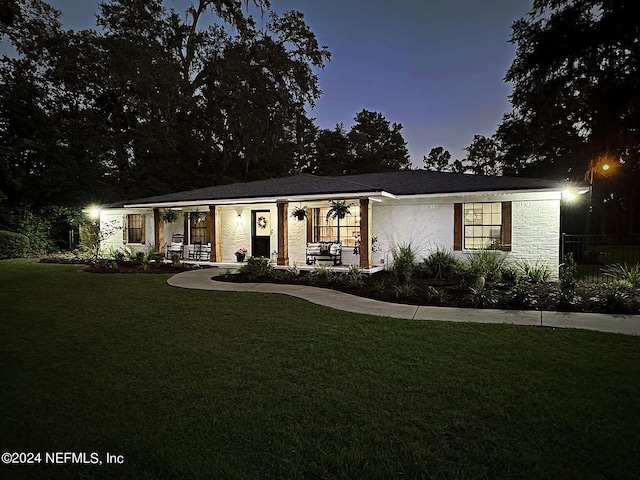 ranch-style home with covered porch and a lawn