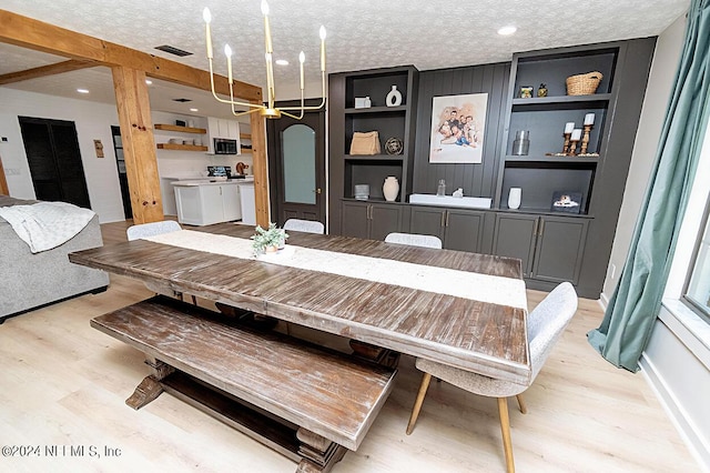 dining room with light wood-type flooring, a textured ceiling, and built in features