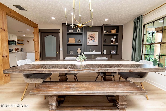 dining area featuring built in shelves, a textured ceiling, and light hardwood / wood-style floors