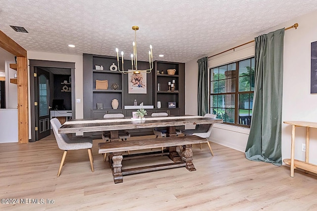 dining space featuring a textured ceiling, light hardwood / wood-style floors, and built in features