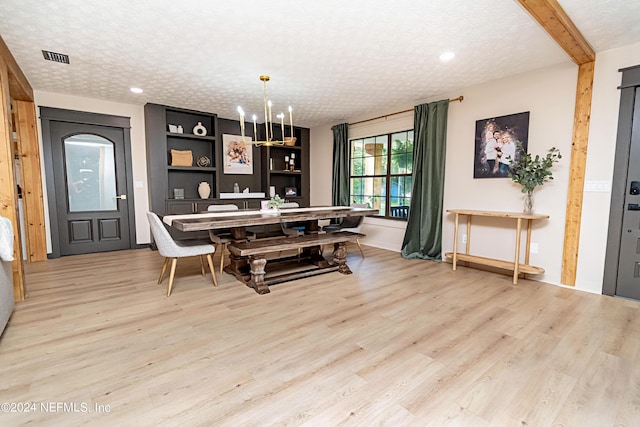 dining space with a chandelier, a textured ceiling, beamed ceiling, and light wood-type flooring