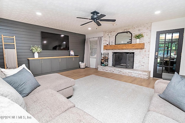 living room with hardwood / wood-style flooring, a textured ceiling, ceiling fan, and a fireplace