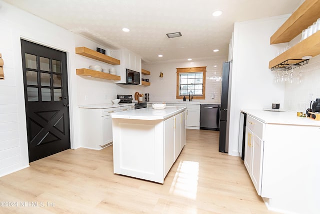 kitchen with light hardwood / wood-style floors, a center island, sink, stainless steel appliances, and white cabinets