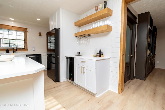 kitchen featuring white cabinetry, light wood-type flooring, wine cooler, black appliances, and sink