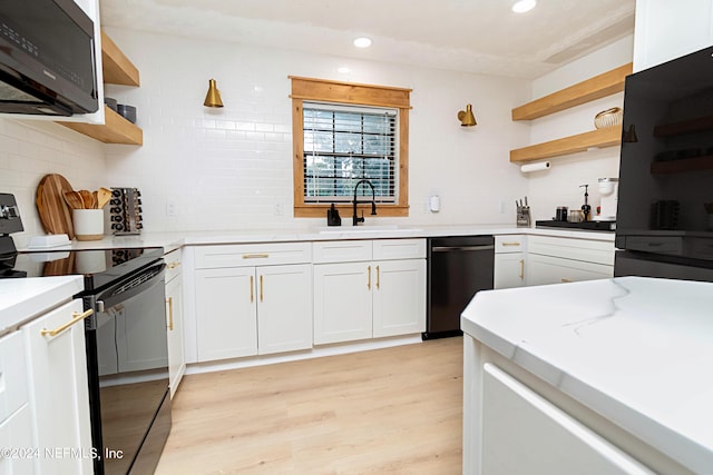 kitchen with white cabinets, black appliances, light hardwood / wood-style floors, sink, and decorative backsplash