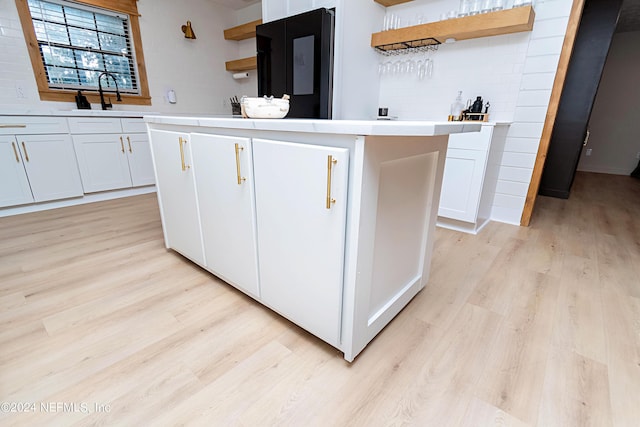 kitchen featuring white cabinetry, decorative backsplash, light hardwood / wood-style floors, and a kitchen island