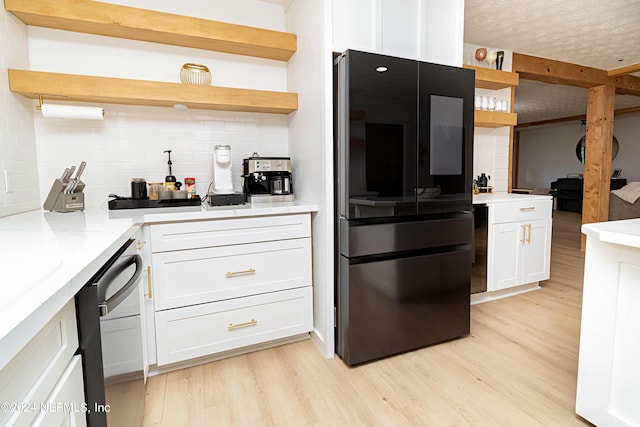 kitchen with decorative backsplash, black refrigerator, white cabinetry, and dishwasher