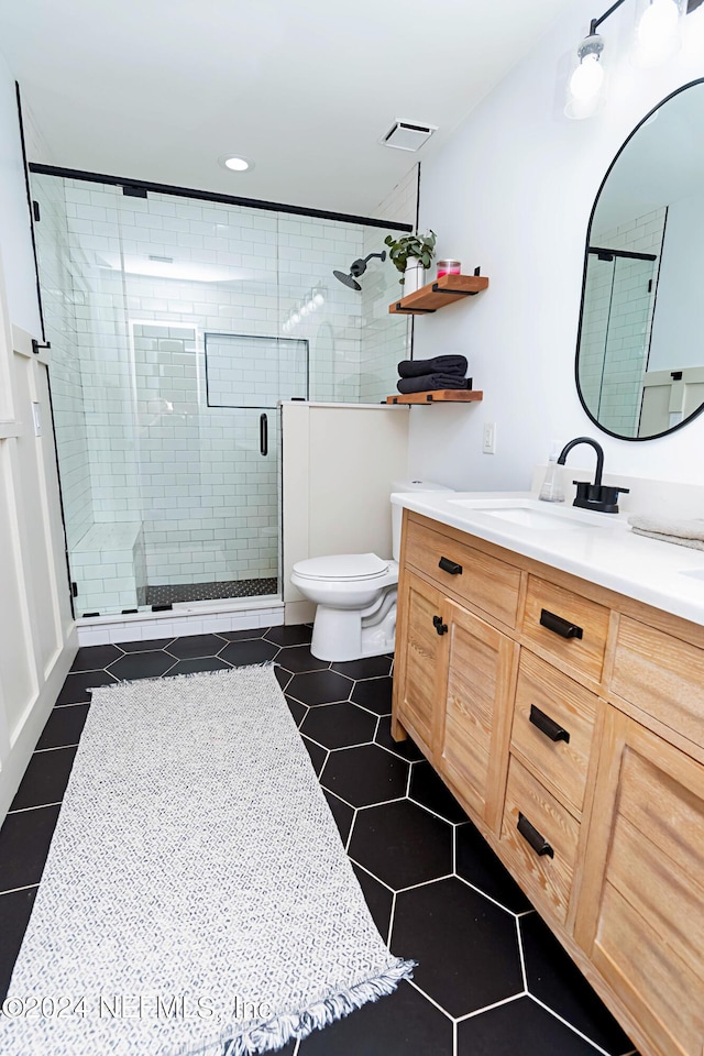 bathroom featuring toilet, vanity, and a shower with door