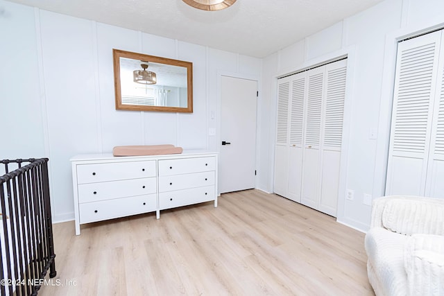 unfurnished bedroom featuring multiple closets, a textured ceiling, and light hardwood / wood-style floors