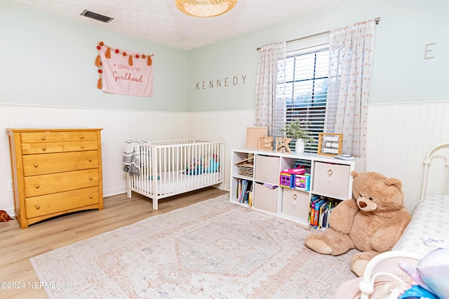 bedroom featuring a textured ceiling, hardwood / wood-style floors, and a crib