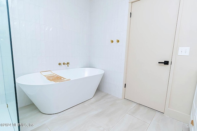 bathroom featuring tile patterned flooring, tile walls, and a tub