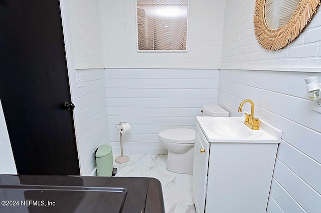 bathroom featuring toilet, vanity, and wooden walls