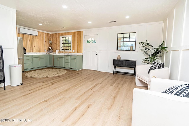 kitchen featuring stainless steel fridge, a wall mounted air conditioner, light wood-type flooring, green cabinetry, and sink