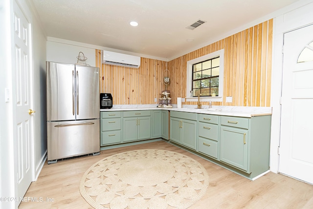 kitchen featuring wood walls, sink, stainless steel refrigerator, a wall mounted air conditioner, and green cabinetry