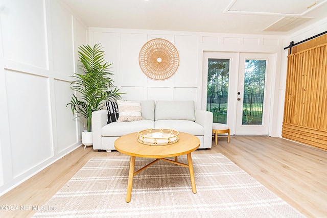 living room featuring a barn door, french doors, and wood-type flooring