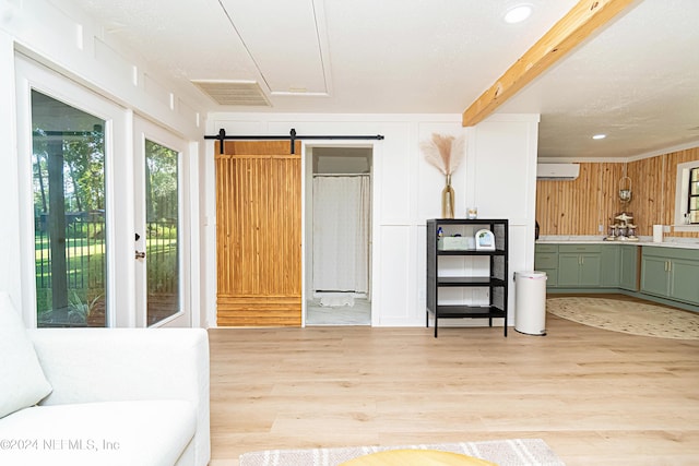 living room with a barn door, wooden walls, a wall unit AC, beam ceiling, and light hardwood / wood-style flooring