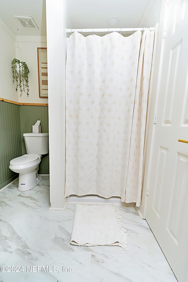 bathroom featuring toilet and wooden walls