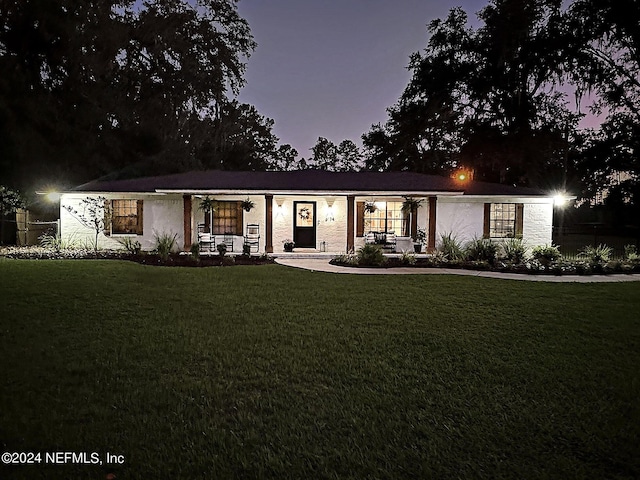 ranch-style home with covered porch and a yard