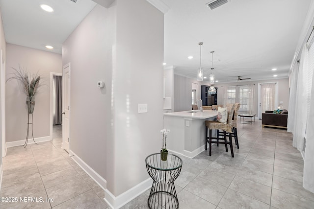 hallway with crown molding, sink, and light tile patterned floors