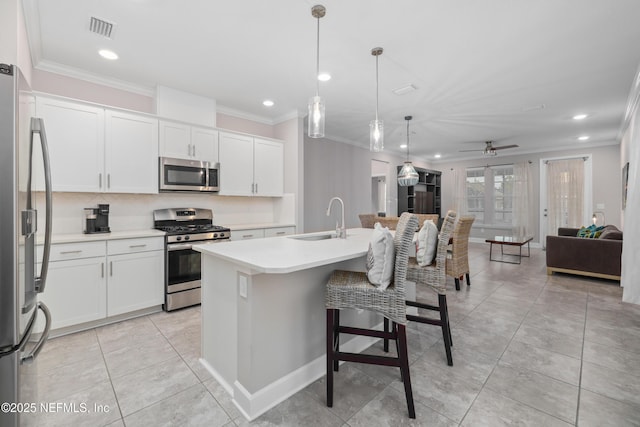 kitchen with a kitchen island with sink, sink, white cabinetry, and appliances with stainless steel finishes