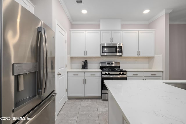 kitchen with crown molding, light stone countertops, white cabinets, and appliances with stainless steel finishes