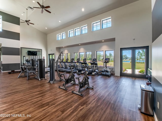 gym with a high ceiling, dark hardwood / wood-style flooring, and french doors