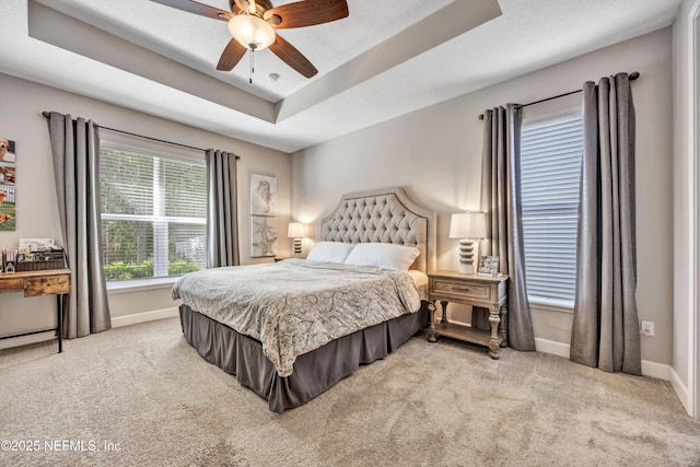 carpeted bedroom featuring a raised ceiling and ceiling fan