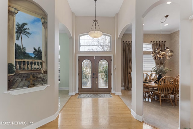 entrance foyer featuring a notable chandelier, a healthy amount of sunlight, french doors, and light wood-type flooring