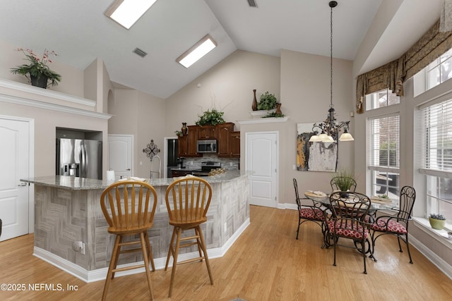 kitchen with a kitchen bar, a notable chandelier, light stone counters, and stainless steel appliances